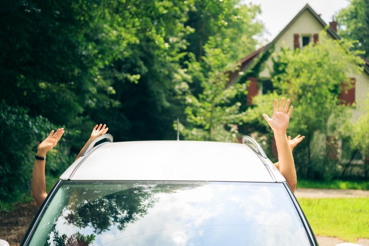People waiving hand from a car