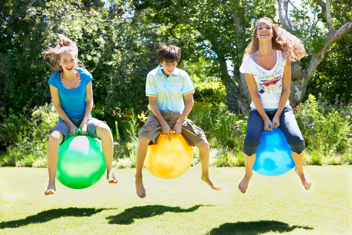 Three friends playing with hopping ball