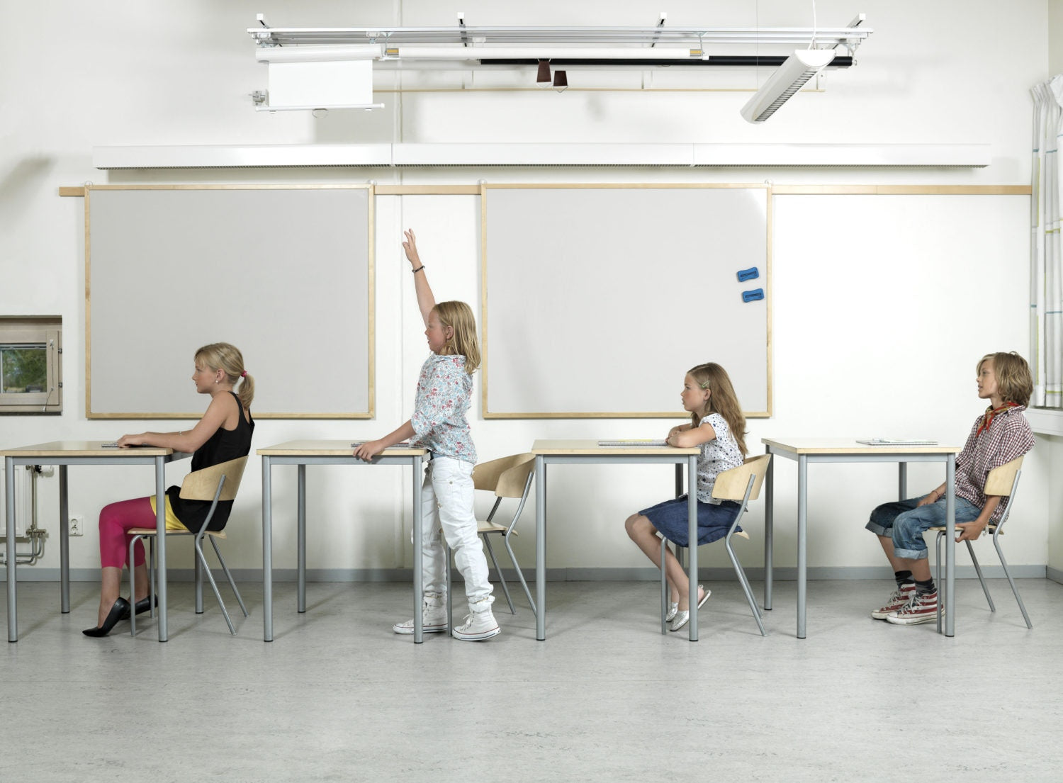 A student raising hand among other students in a class