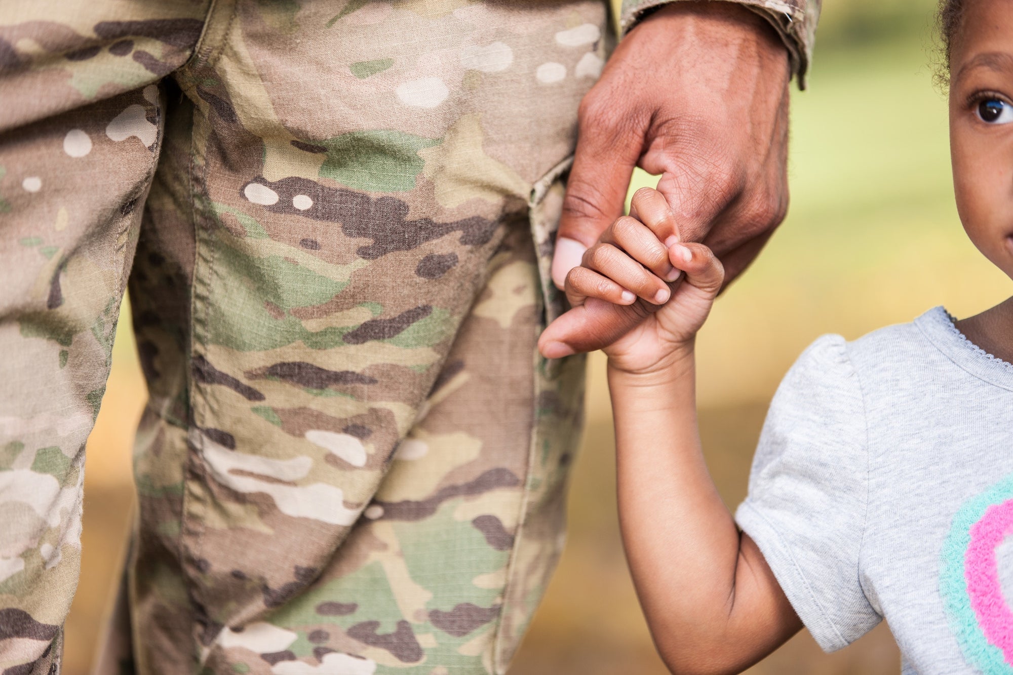 young girl holding a service man's hand