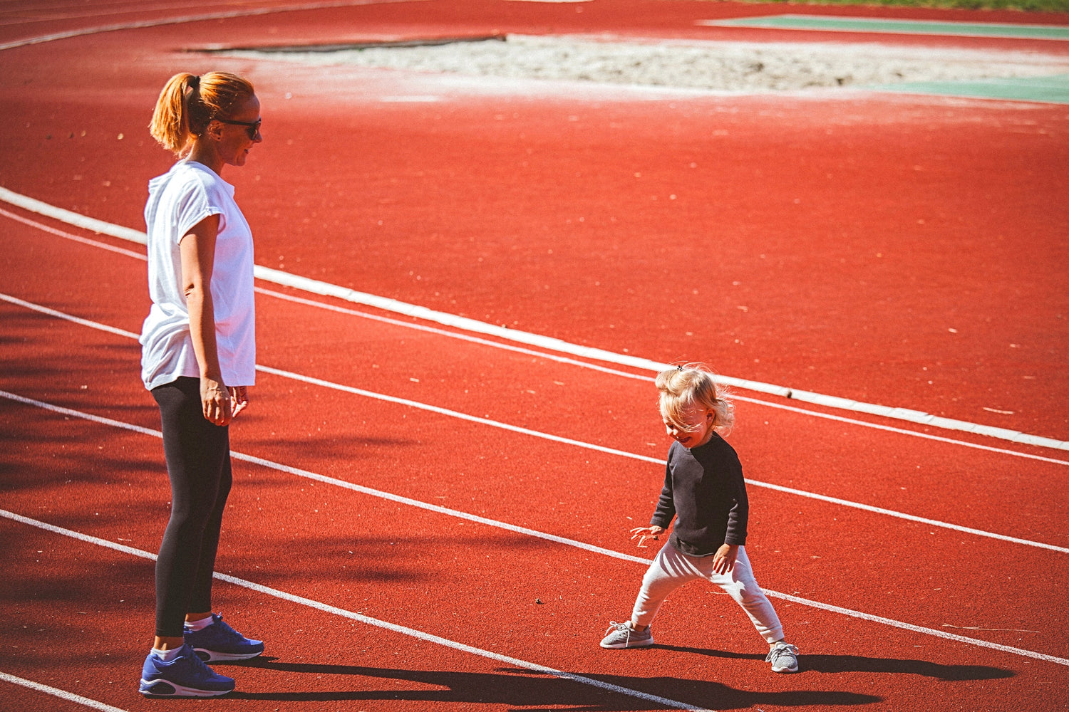 yong mother and little daughter standing in running court