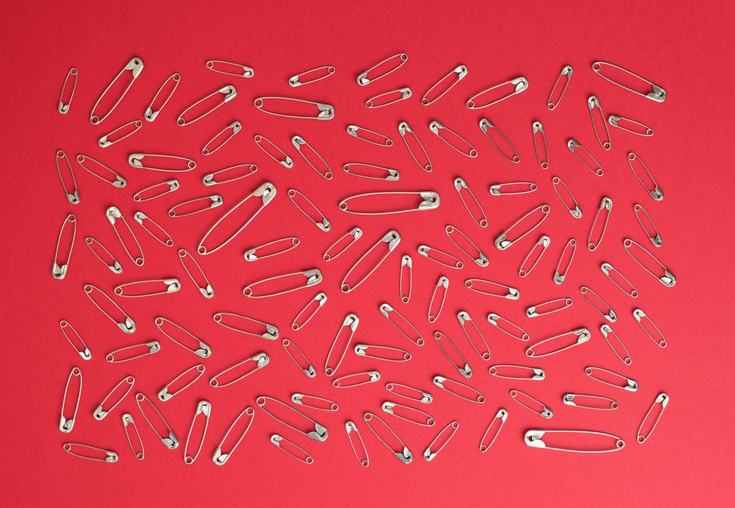 lots of safety pins over red background