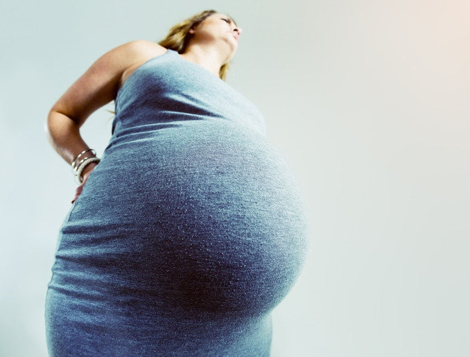 belly of a pregnant women in a blue dress