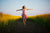 Young  woman jumping in the middle of a field with yellow flowers