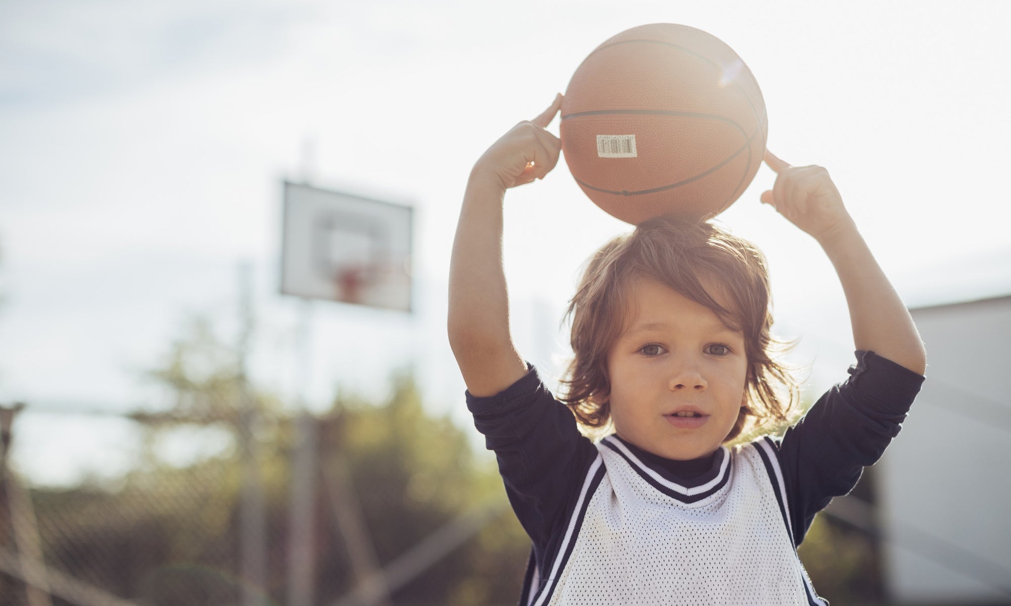 Child holding the basket ball on his head 