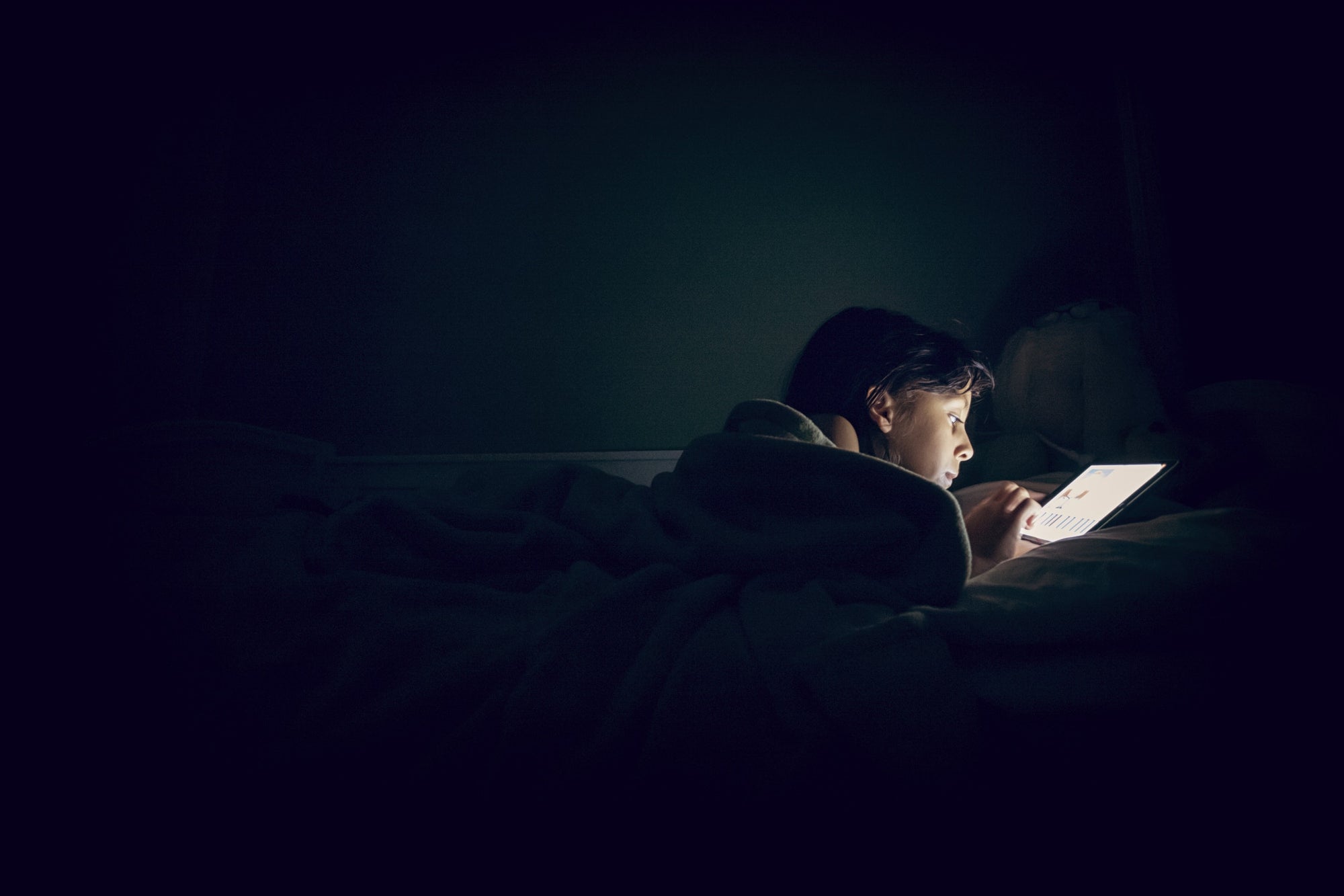 A person using tab in bed in a dark room