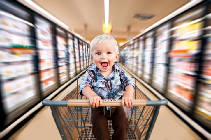 A child sitting on a shopping cart moving fast