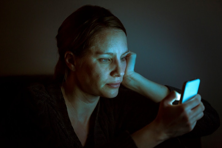woman gazing at a smartphone in the dark