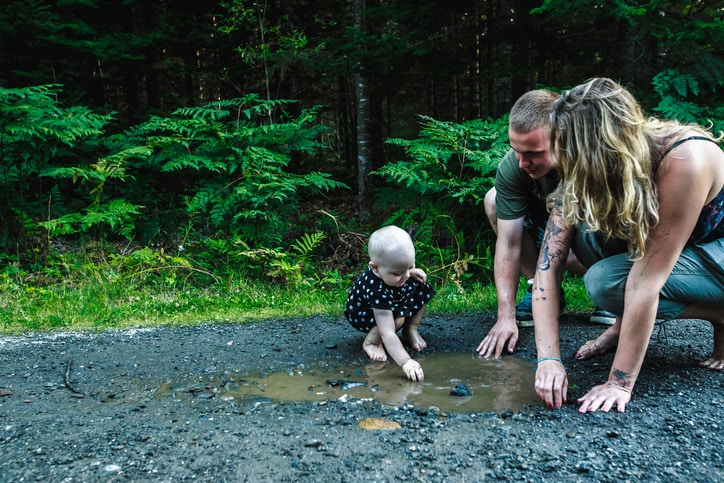 parents with cute little baby playing in mud