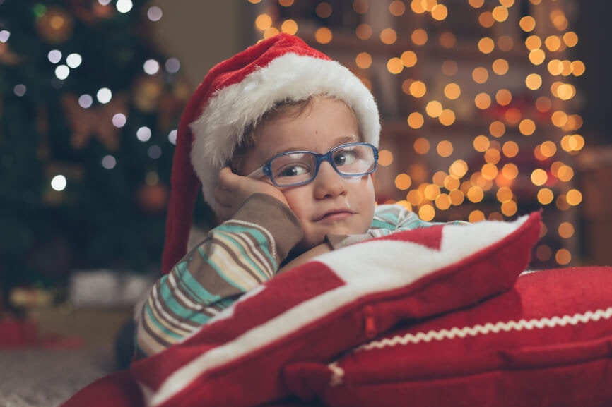 young boy with Santa Hat on resting his head on two pillows