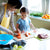 young girl looking at their mother who is cutting vegetables in the kitchen