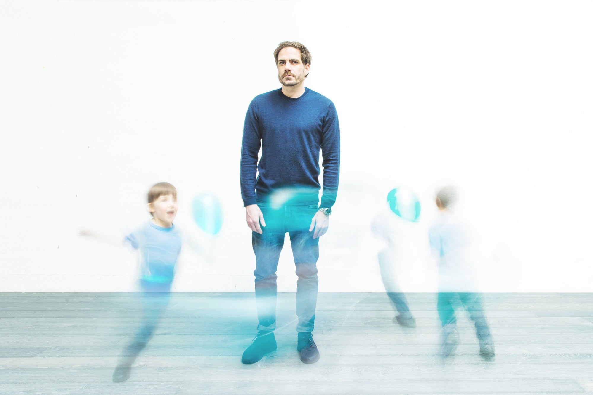 man standing and blur image of kids playing