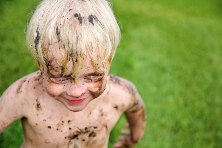 happy young boy covered in dirt and mud