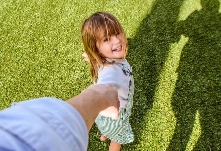 little girl holding her father's hand smiling at him