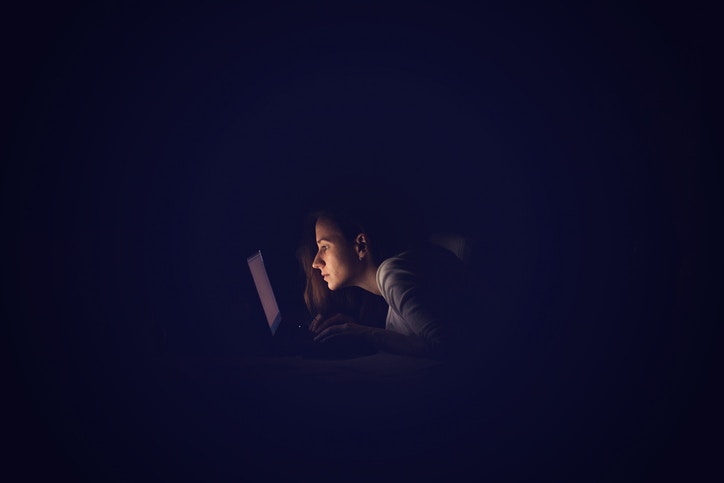 woman looking at her laptop screen sitting in night