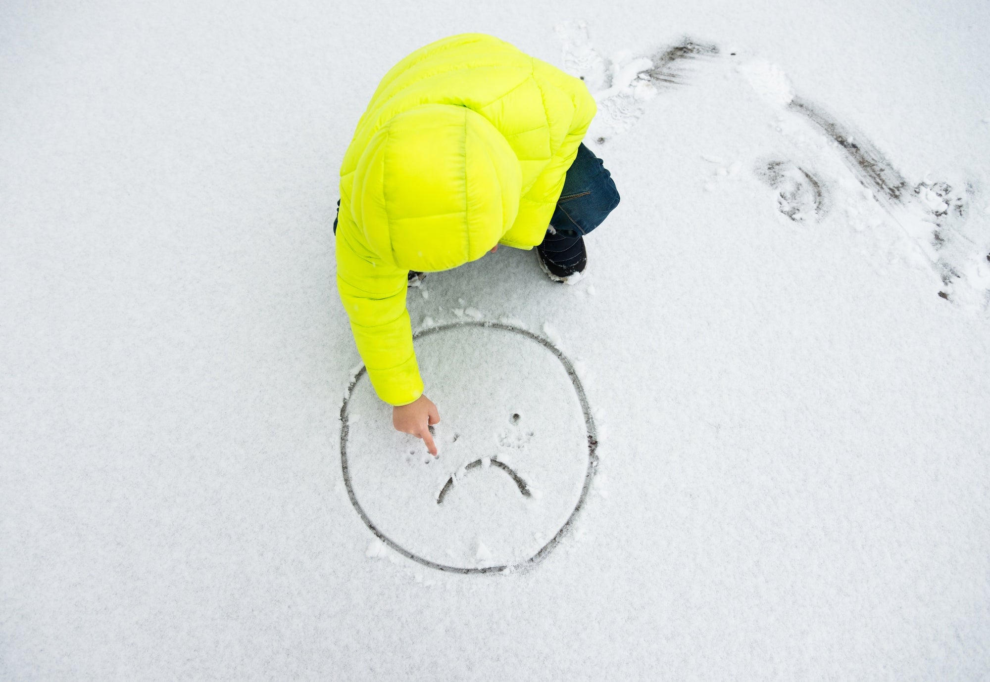A child making sad emoji in snow
