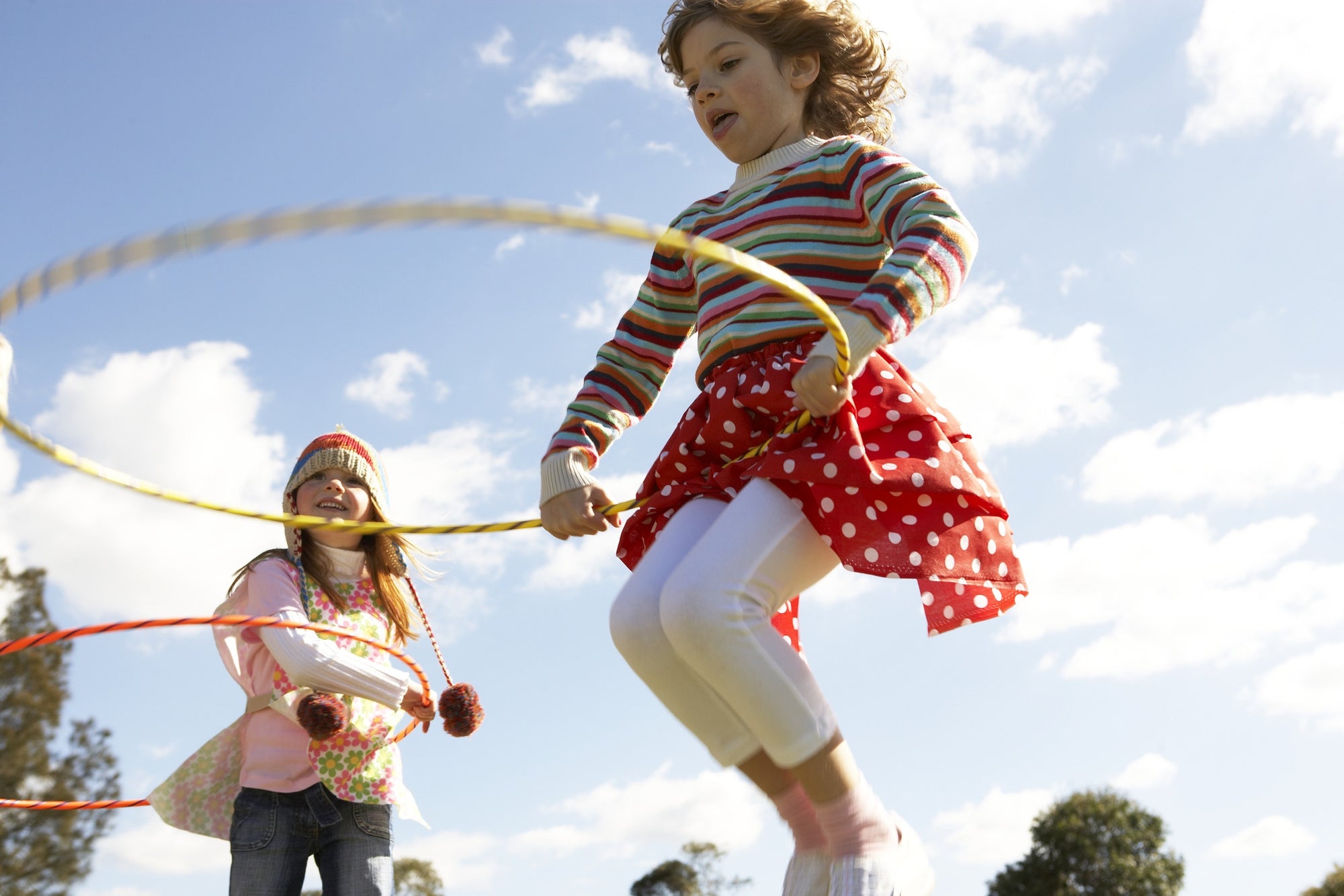 Young Girls playing with hula hoop in summer field