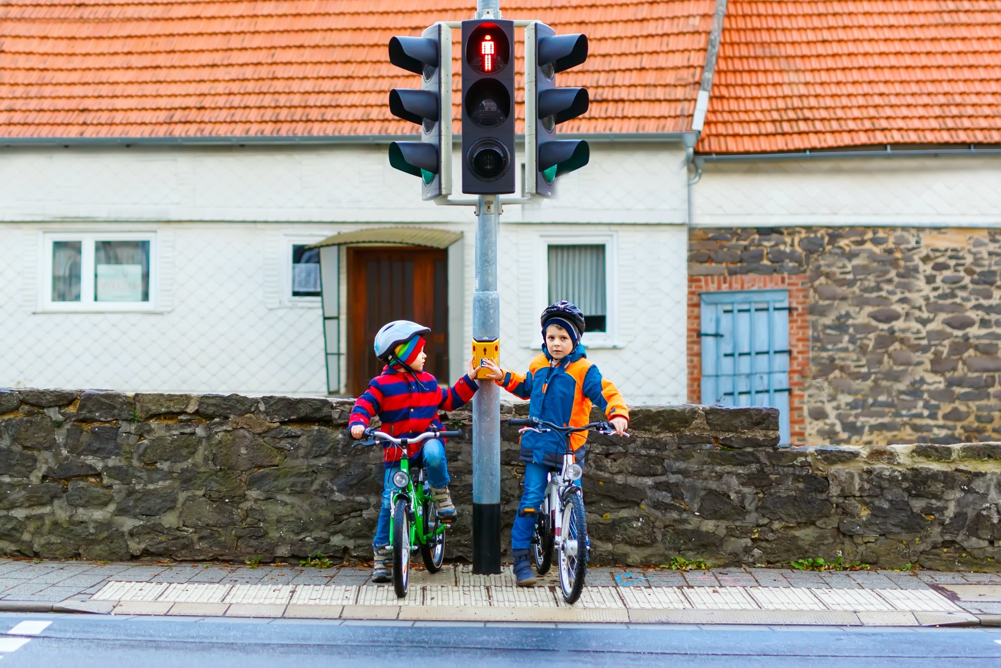 Two kids boys biking and waiting on traffic light
