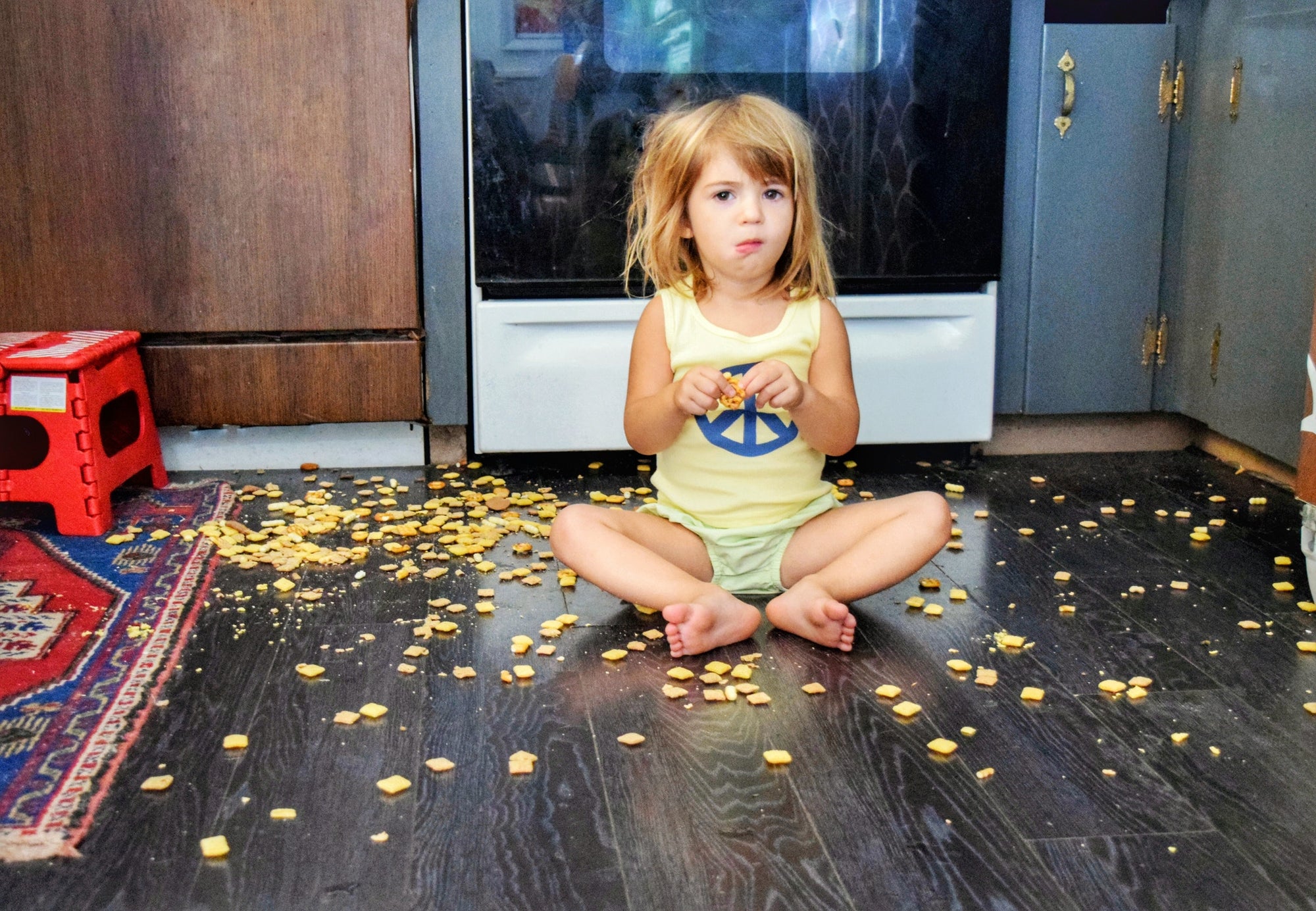 little girl eating snacks off the floor