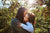 mother is kissing her daughter on the cheek, apple trees on the background