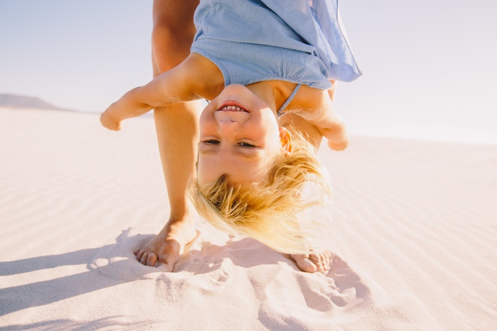 parent holing young blonde girl upside down 