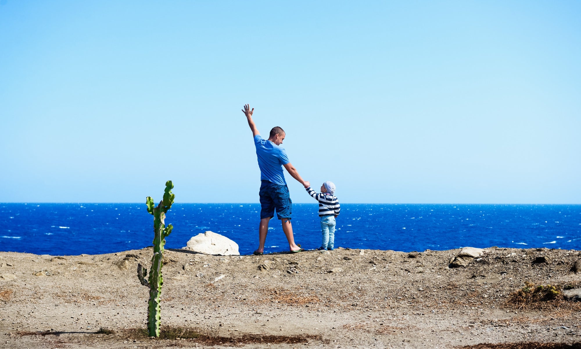 young man and a boy facing  the ocean