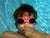 young boy wearing swimming googles and holding his breath underwater in apool