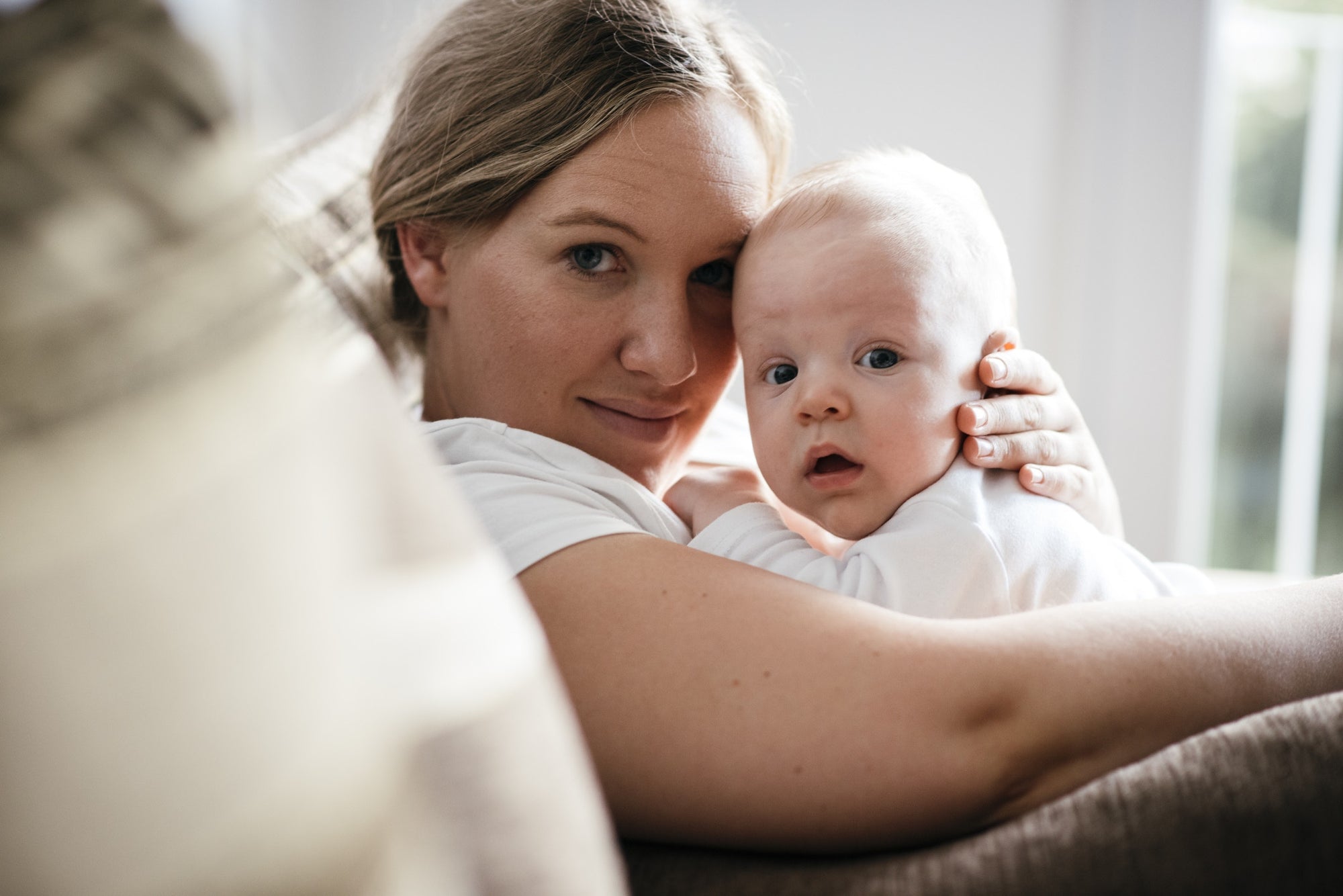 Surprised baby is lying on his mother's chest