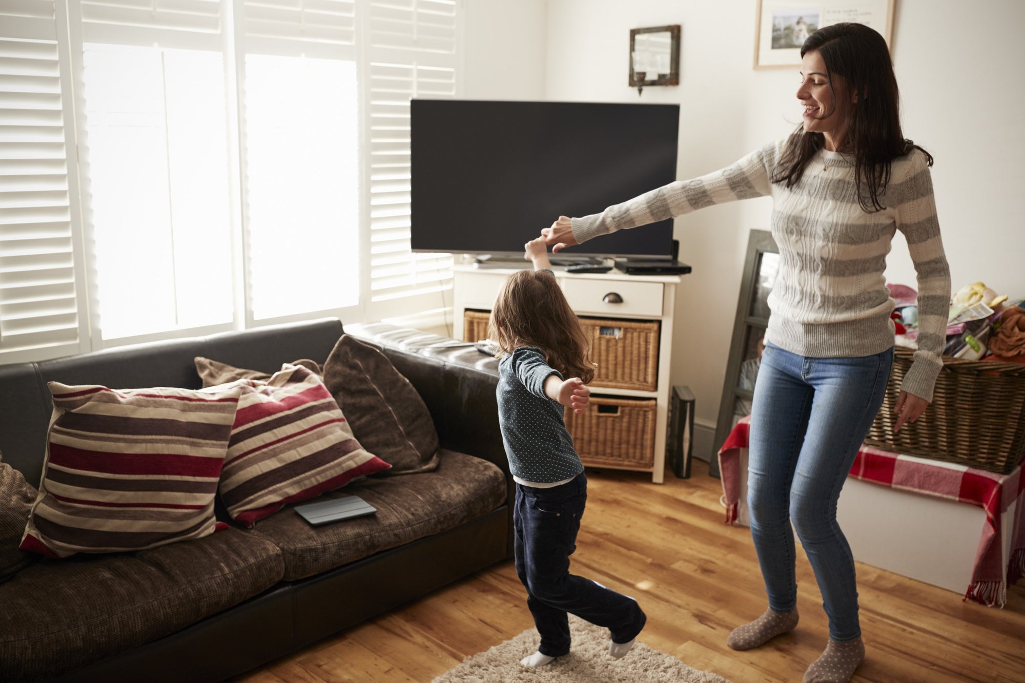 Mother and daughter dancing together in living room