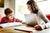 Mother helping son while he is studying and she is working on laptop at home 