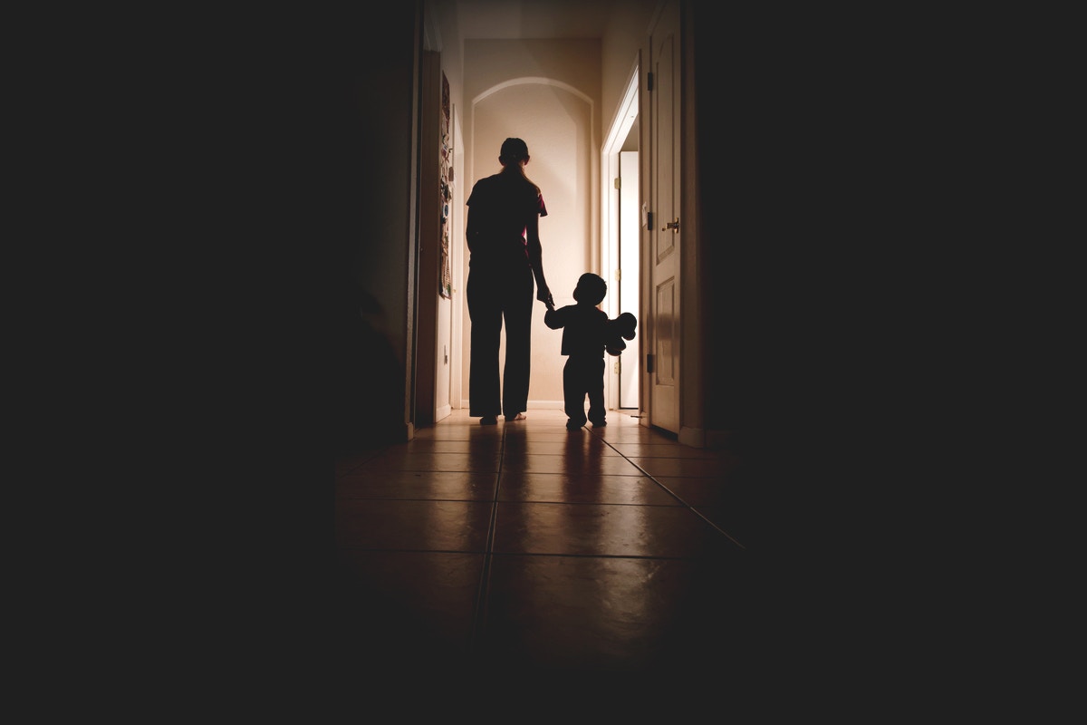rear view of baby child holding mother hand walking on hallway
