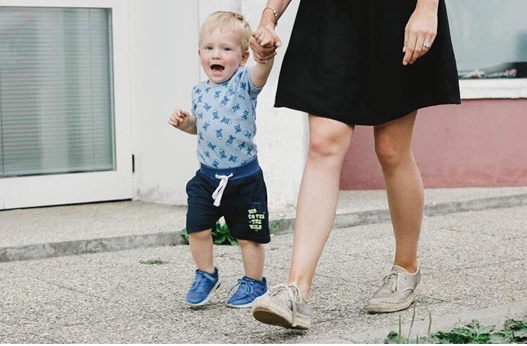Baby child holding mother hand walking on road
