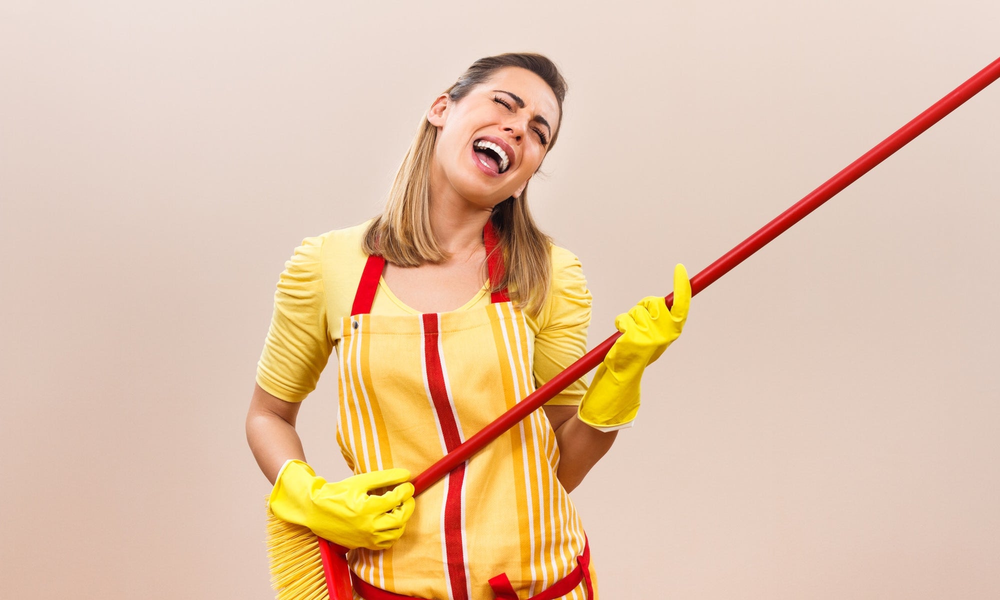 young lady teenager holding a big broom in her hands pretending it is an air guitar