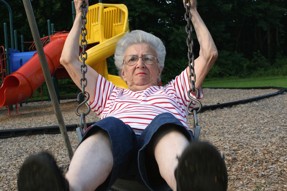 senior citizen woman swinging on a playground swing