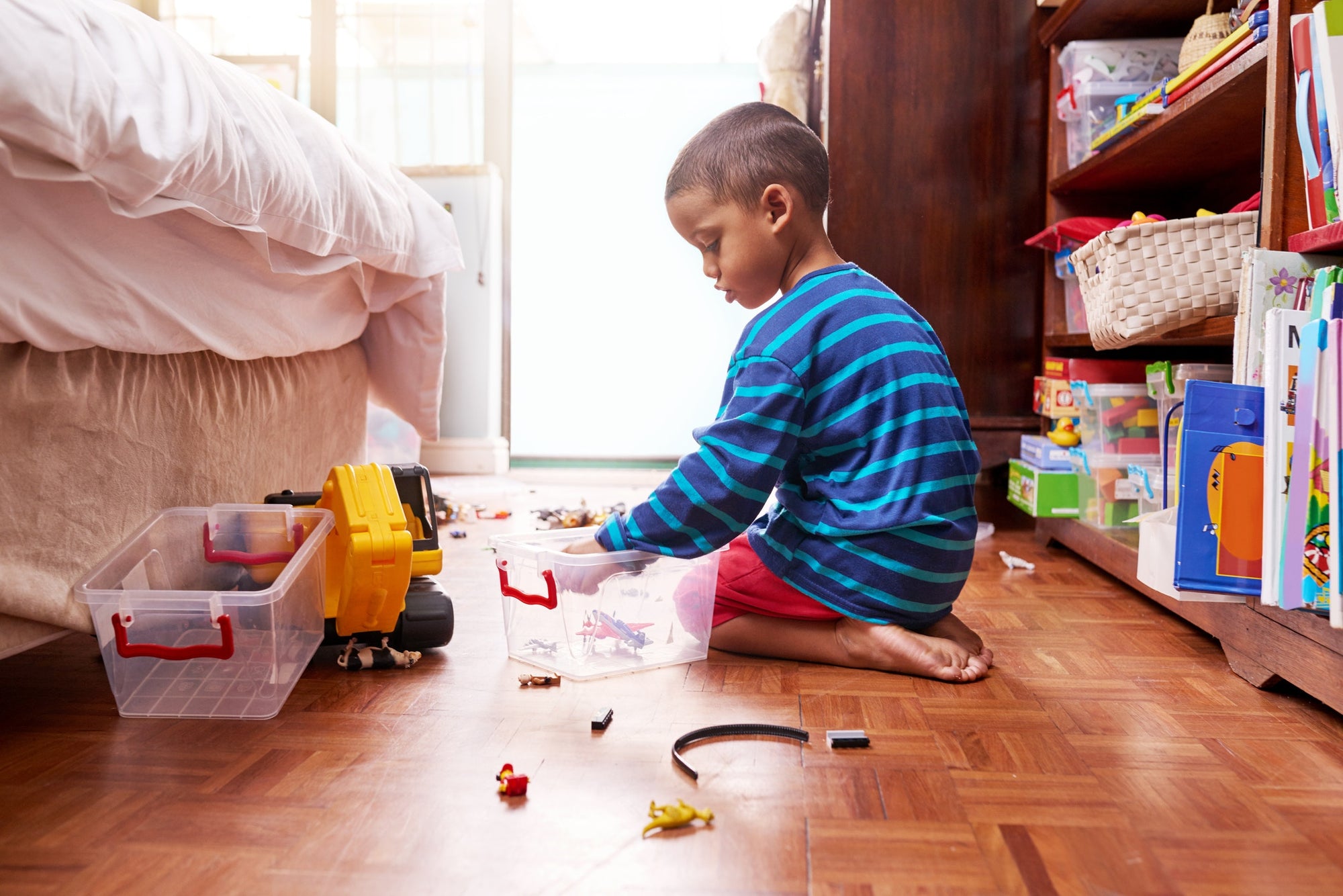 little boy sitting on bedroom floor and playing with toys