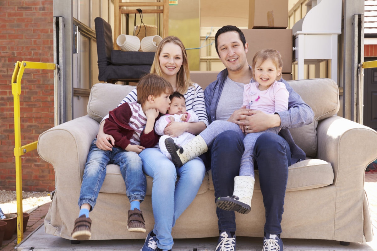 Happy family with kids seated on couch posing for camera