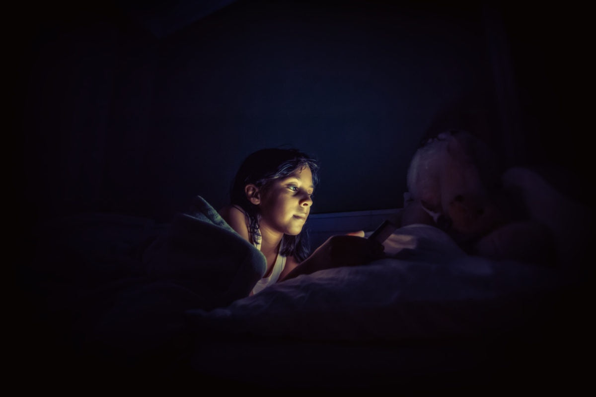 Girl using tab in bed at night