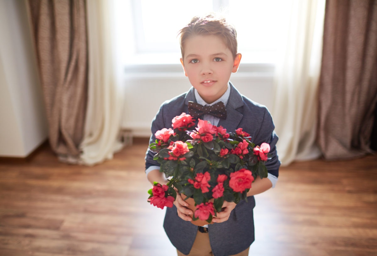 A boy is welcoming some one with flower bouquet