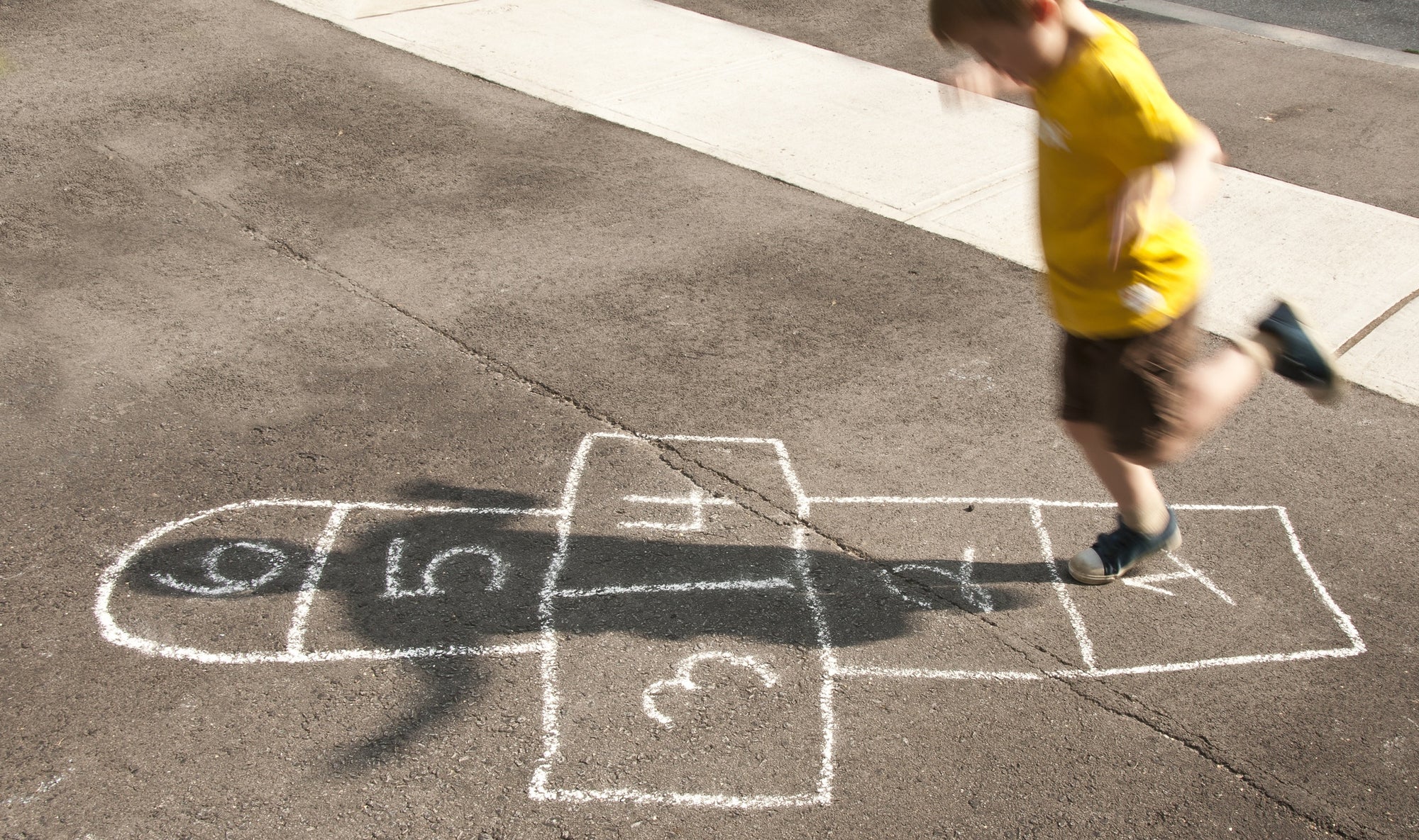 A boy is playing Hopscotch
