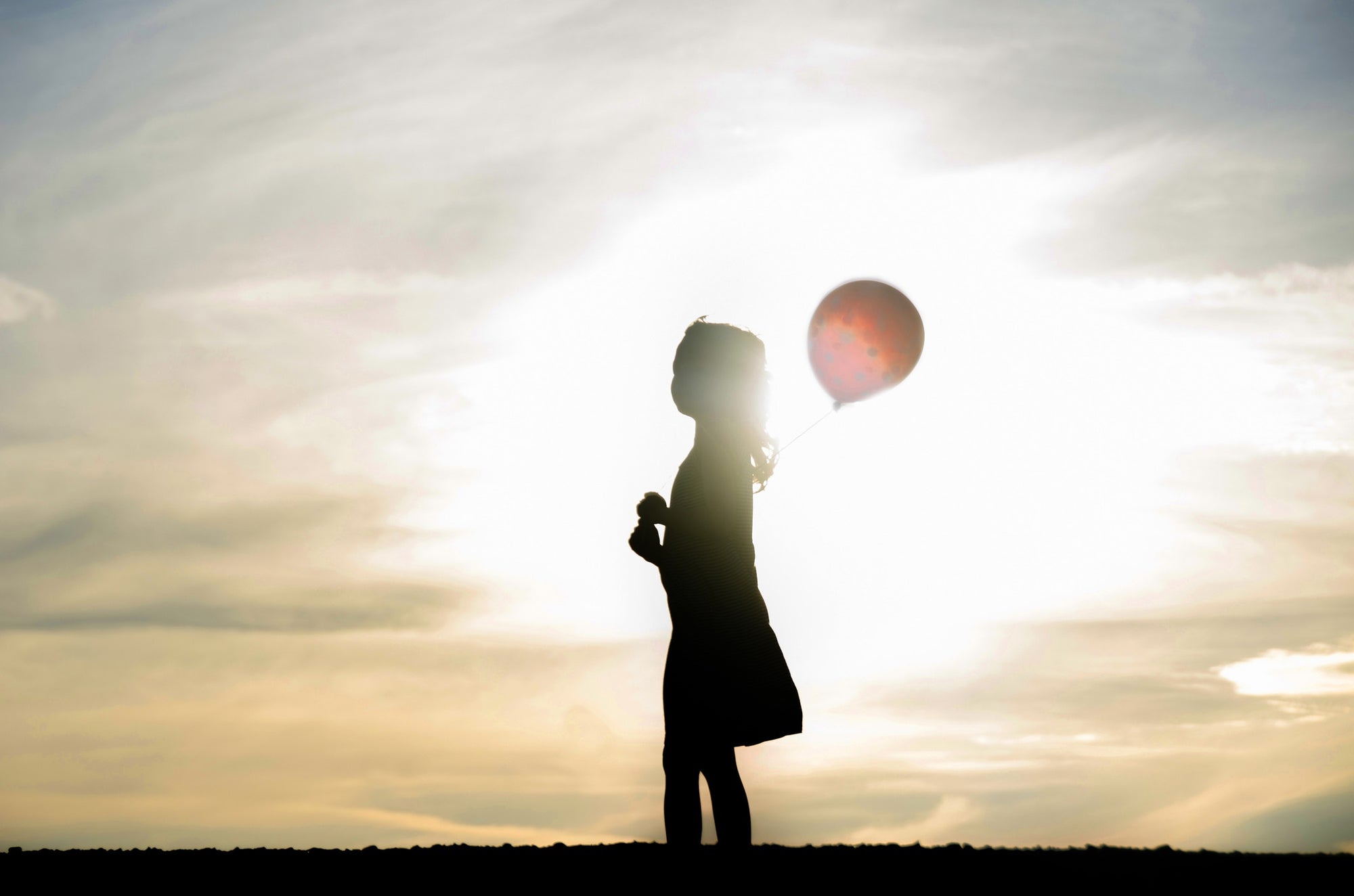 A girl is playing outside in a sunshine with ballon