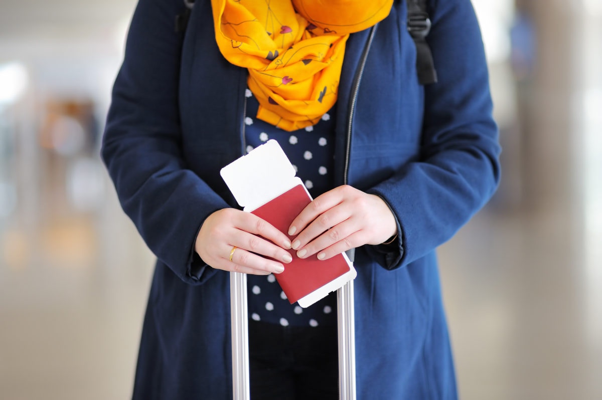Woman wearing black jacket holding a passport