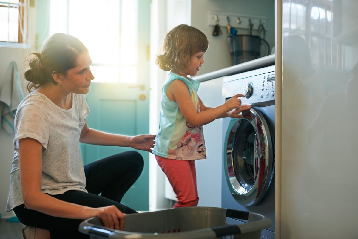 Little girl helping her mother to do laundry