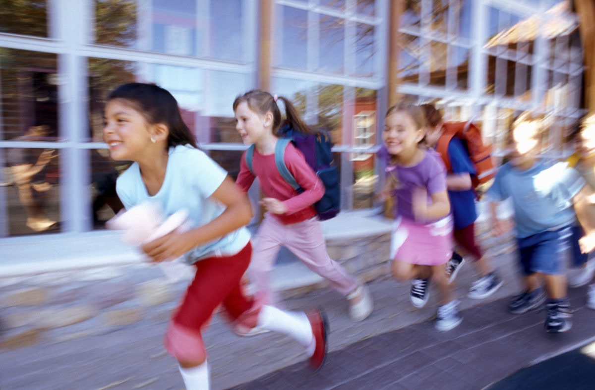 group of school kids wearing backpacks and running forward