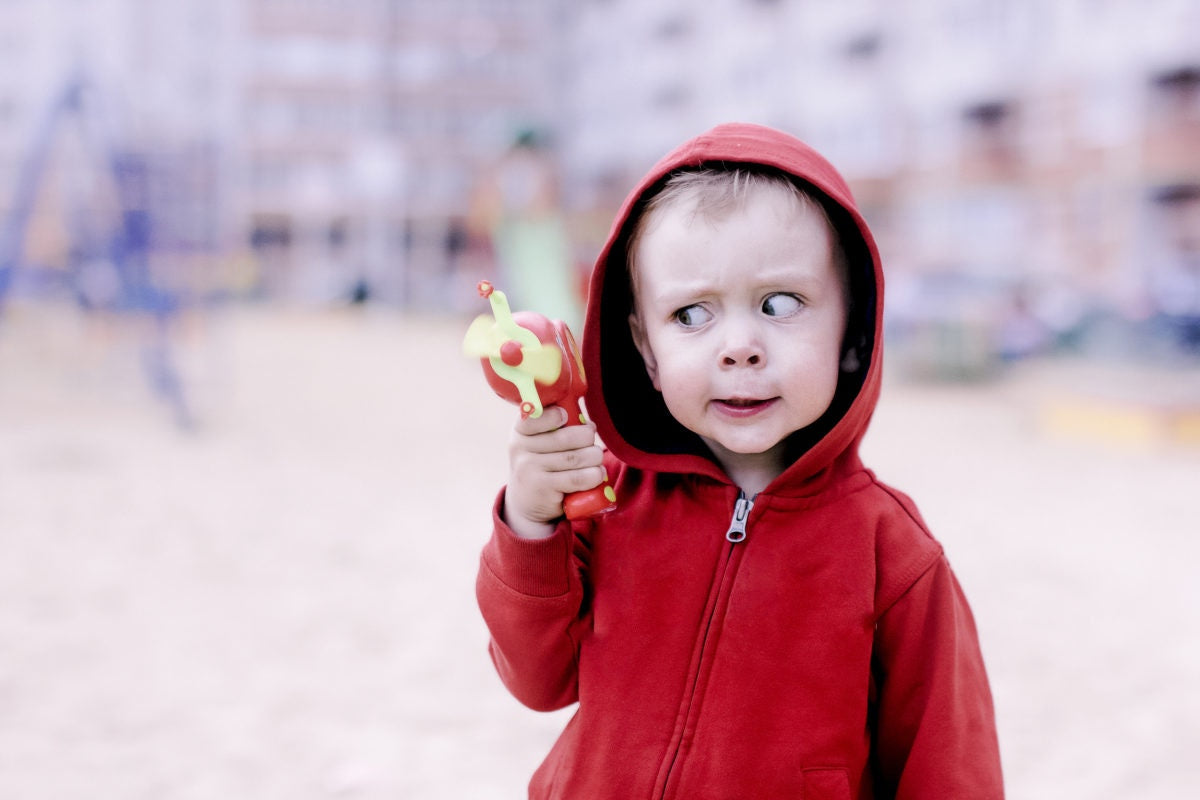 curious boy in red hoodie looking at his toy gun