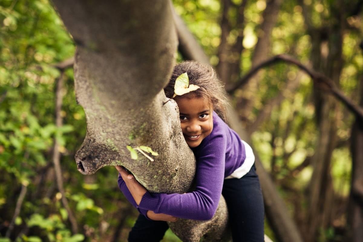 Little girl sitting on tree branch