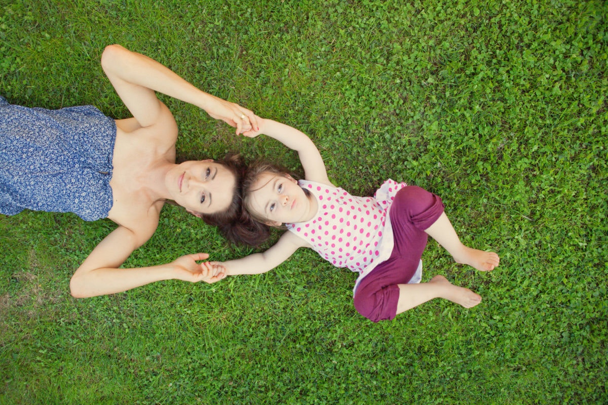 mother and daughter touching heads as they lie on the ground