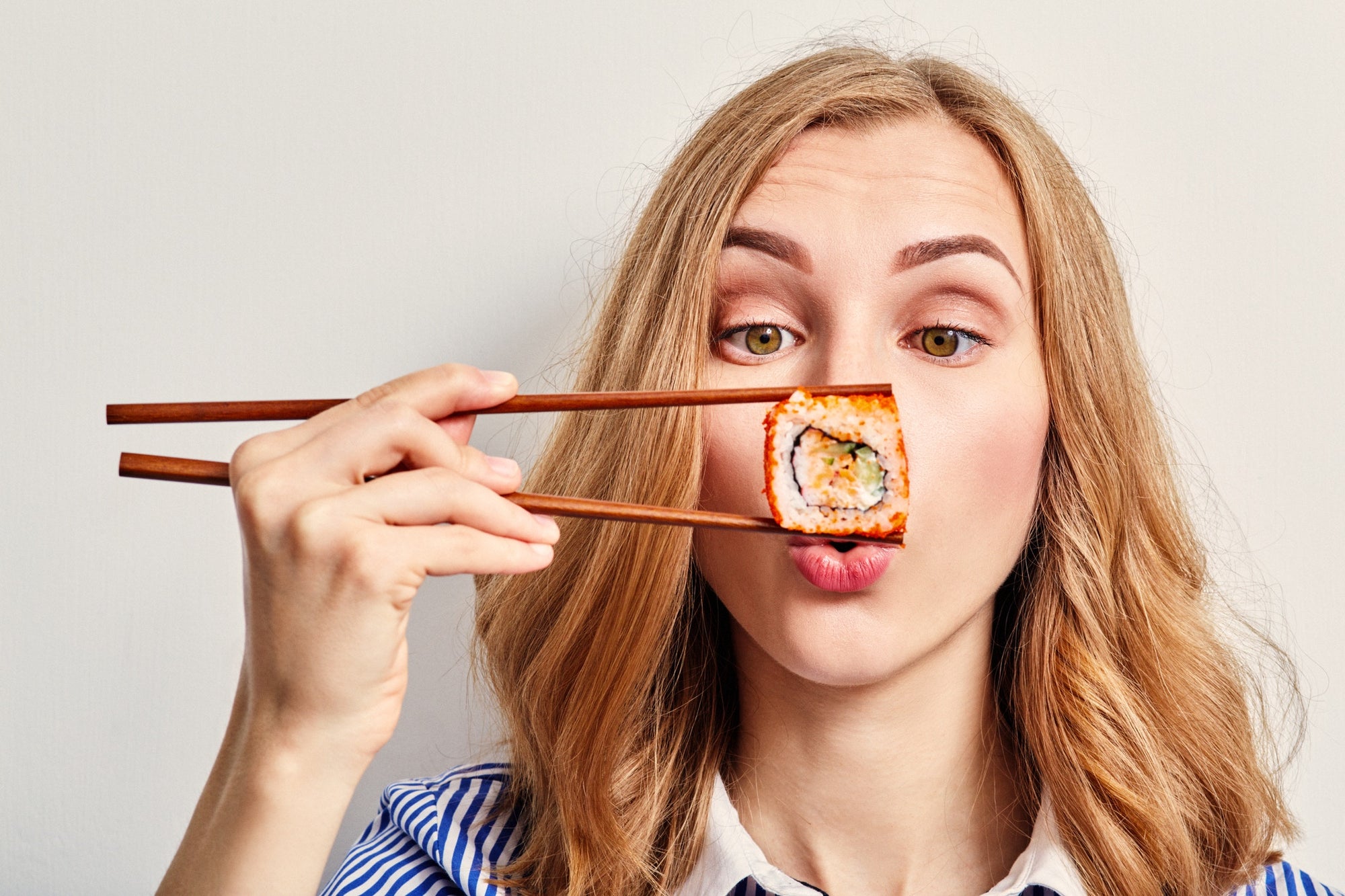 woman eating sushi with chopsticks
