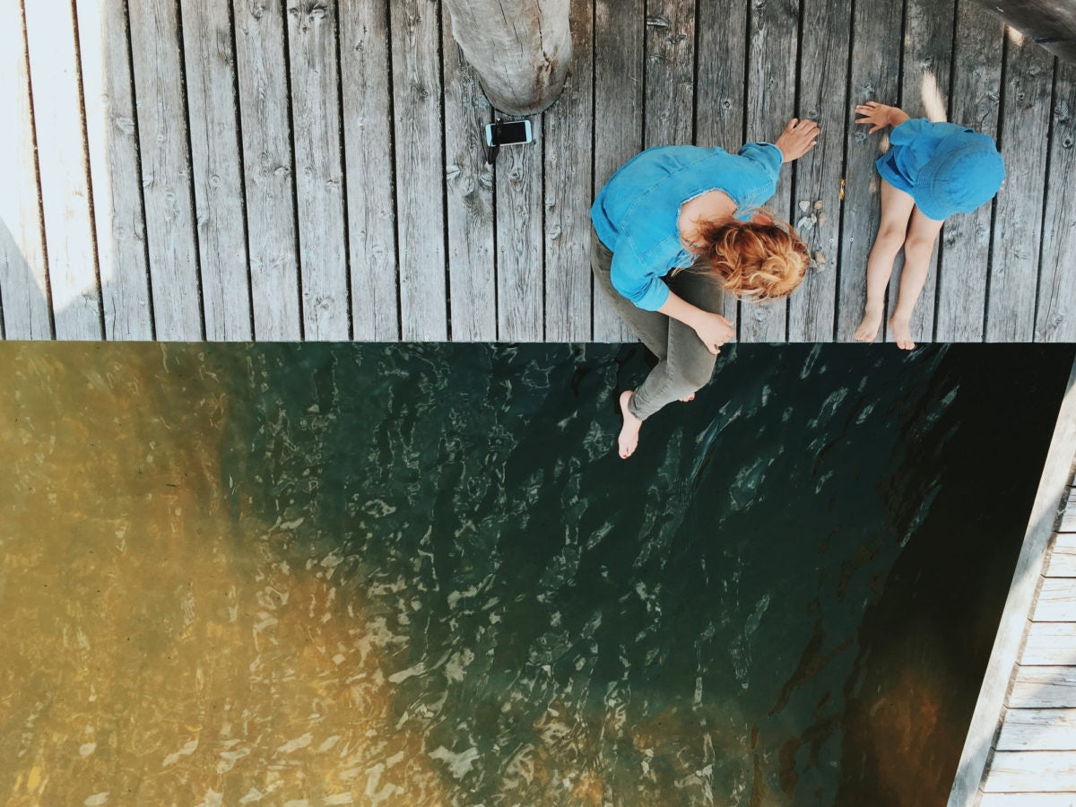 top view of mother and son sitting on a wooden dock lake side.