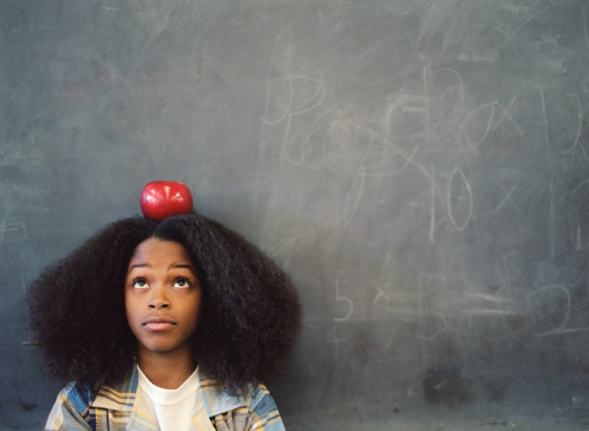 A girl is placing apple on her head and focusing to it