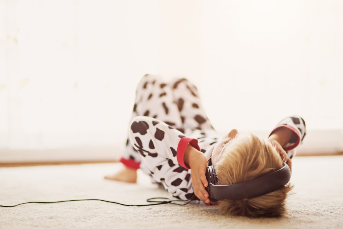 A kid is listening to music by lying on floor